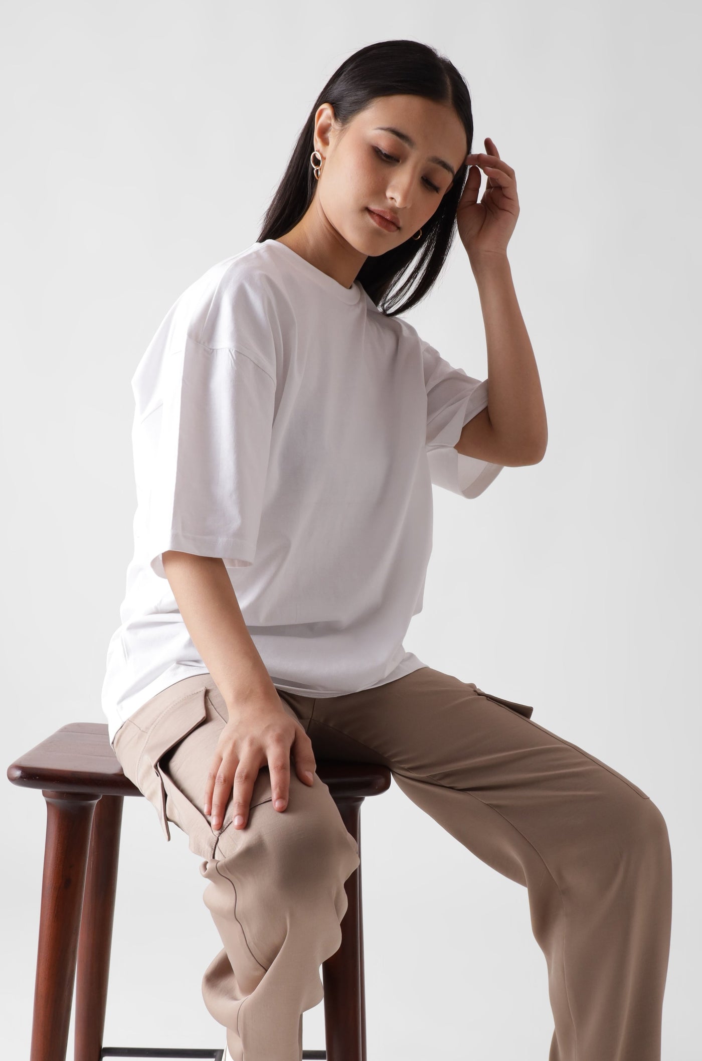 Classic oversized white tshirt for women - sitting on a chair front view - unbound crew