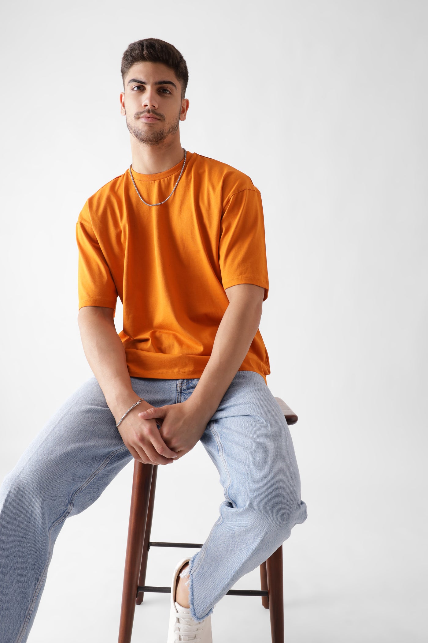 Classic oversized orange tshirt for men - sitting on the chair - unbound crew