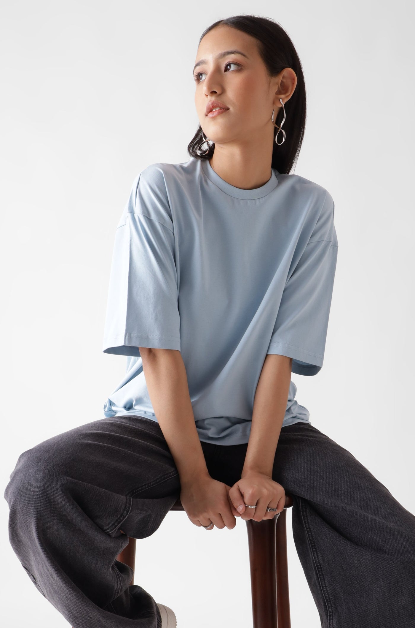 Classic oversized ice blue tshirt for women - sitting on a wooden chair - unbound crew