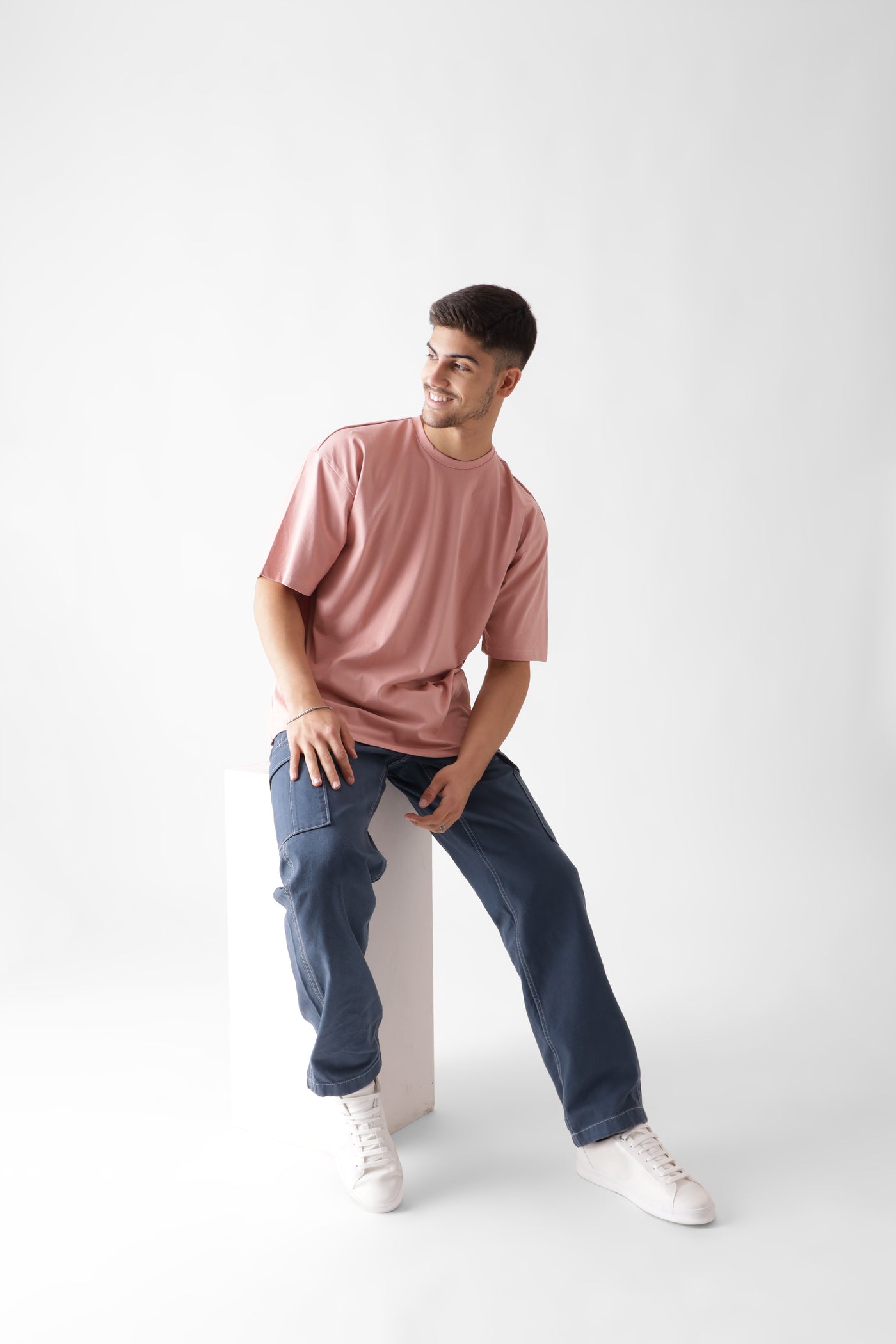 Classic oversized dust pink tshirt for men - sitting on a wodden log - unbound crew