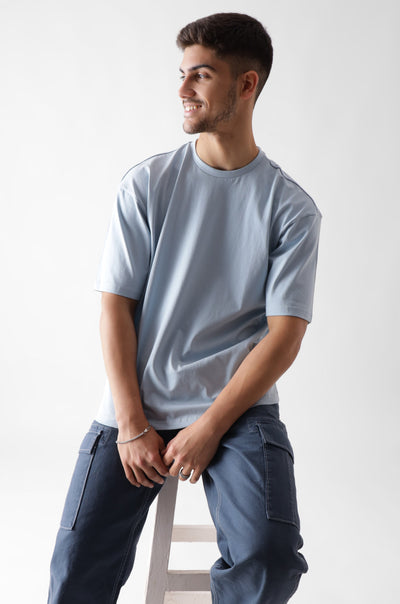 Classic oversized ice blue tshirt for men - sitting on a wooden chair - unbound crew